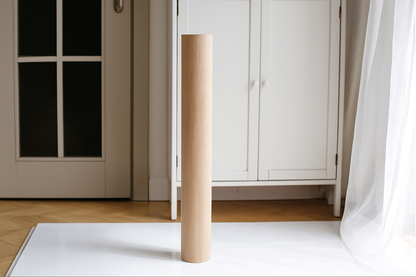 Wooden leg of a piece of furniture on a white rug with a neutral background