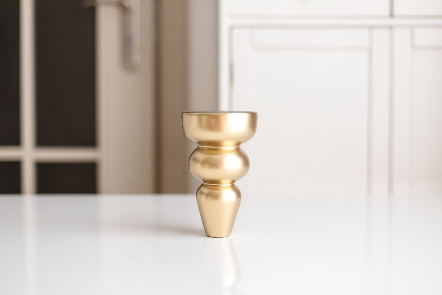 Gold decorative vase on a white surface with a blurred background